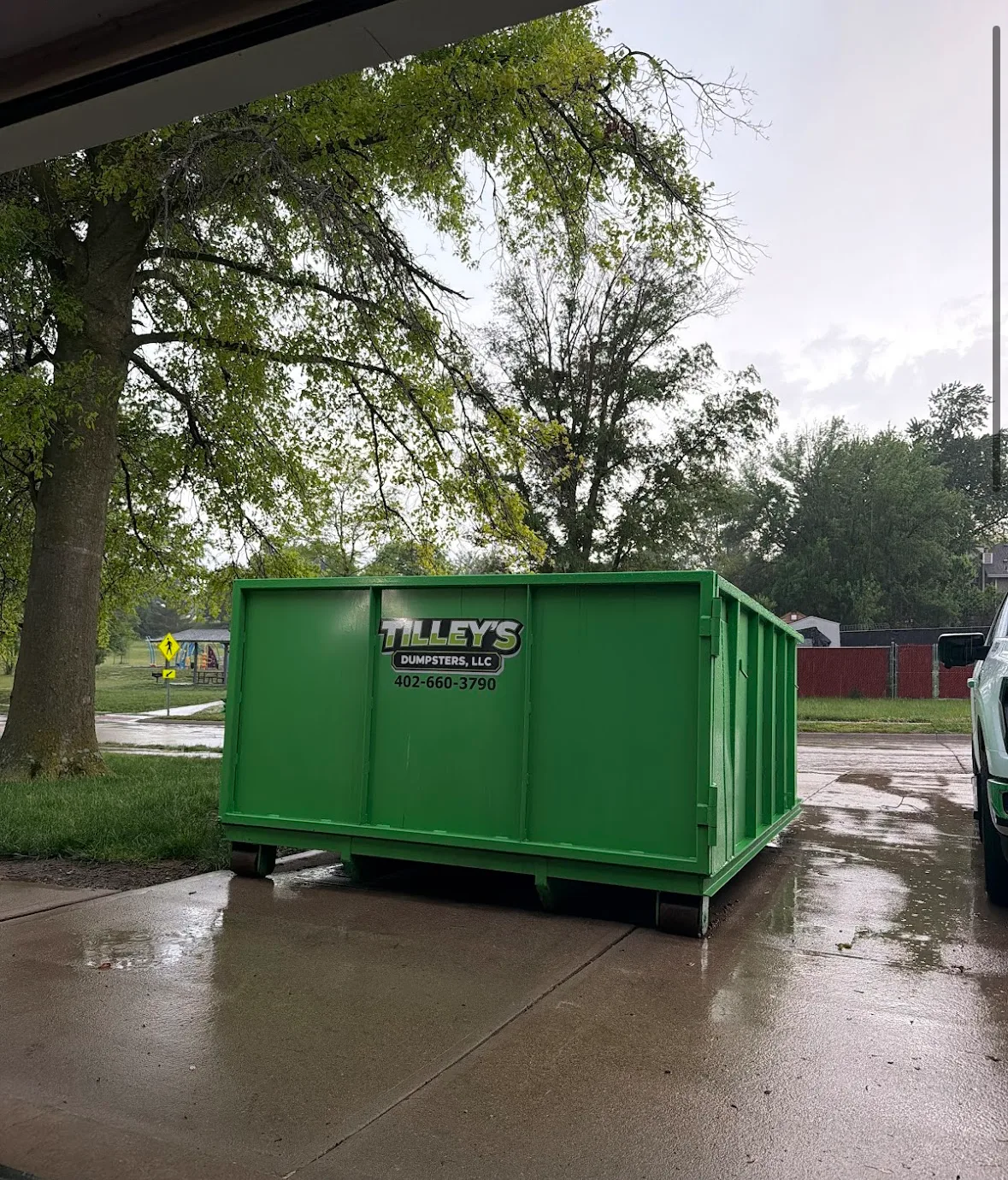 Tilley's dumpster near a neighborhood park in the rain