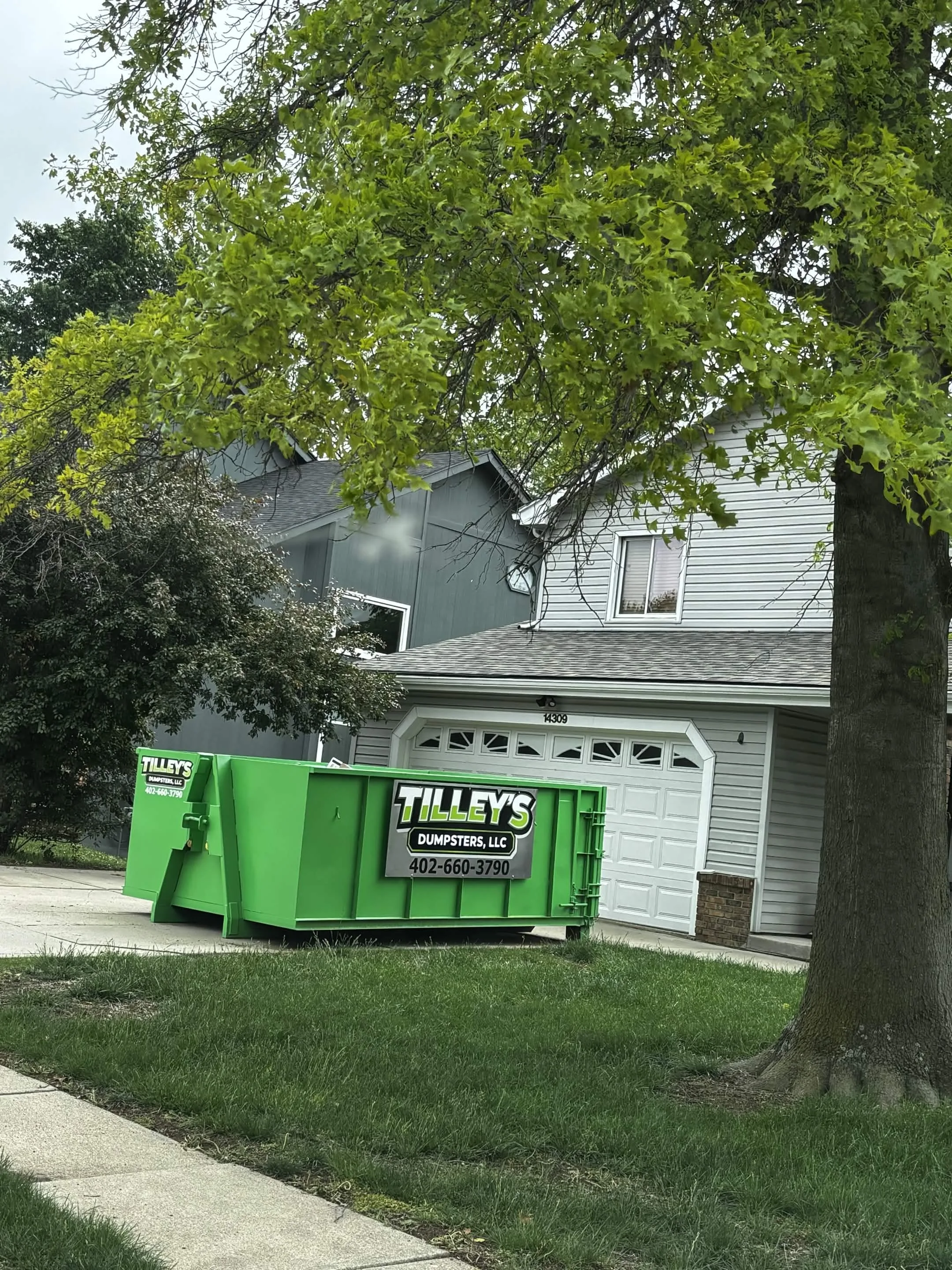 Tilley's dumpster in a residential driveway near a garage