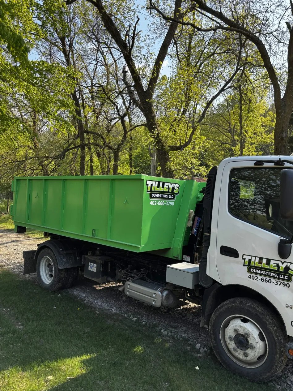 Tilley's truck hauling a green roll-off dumpster